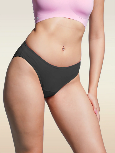 Person wearing black underwear and a pink bra on a beige background
