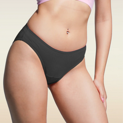 Person wearing black underwear and a pink bra on a beige background