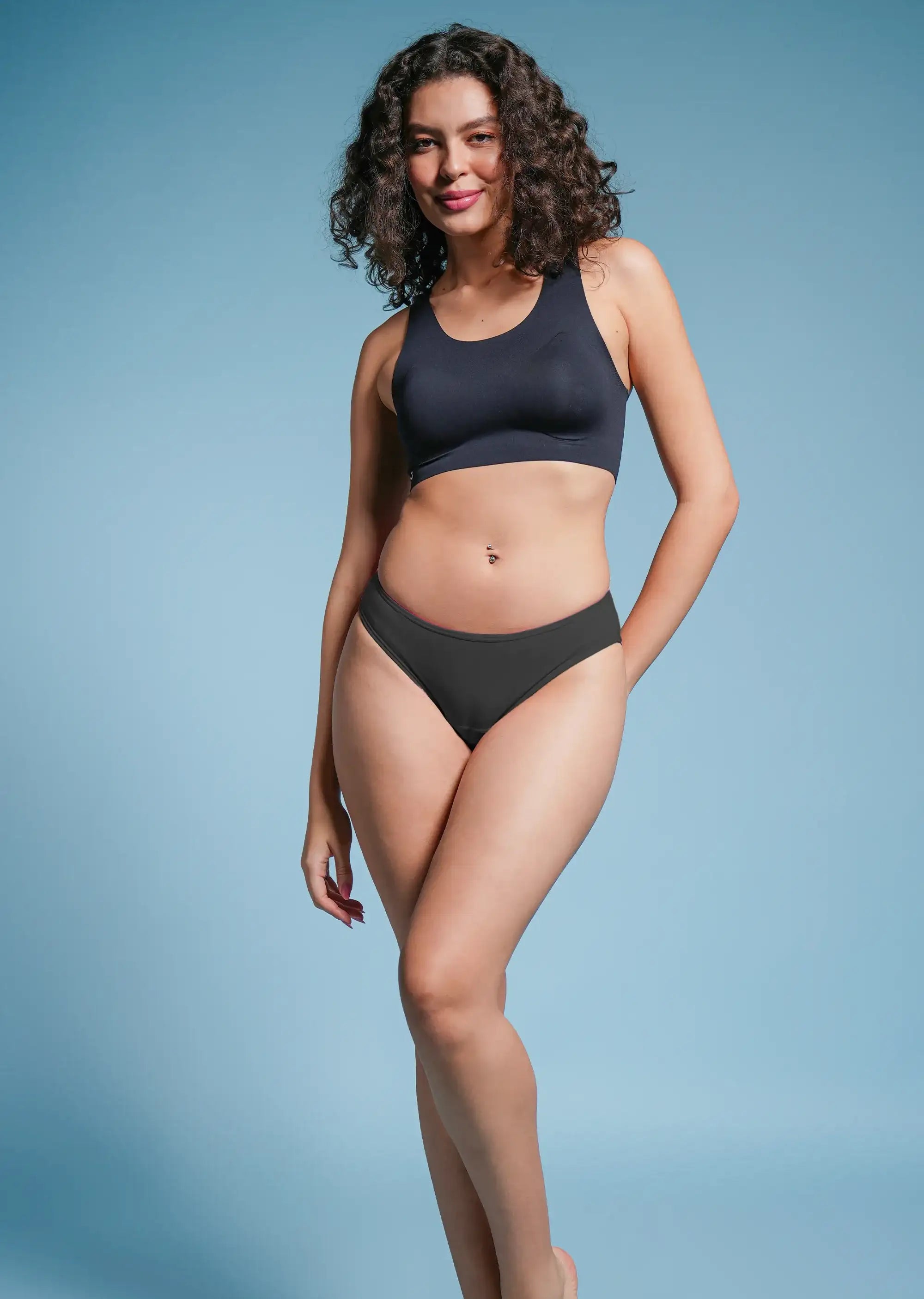 Woman wearing a black bra and underwear against a light blue background