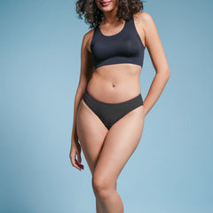 Woman wearing a black bikini against a light blue background