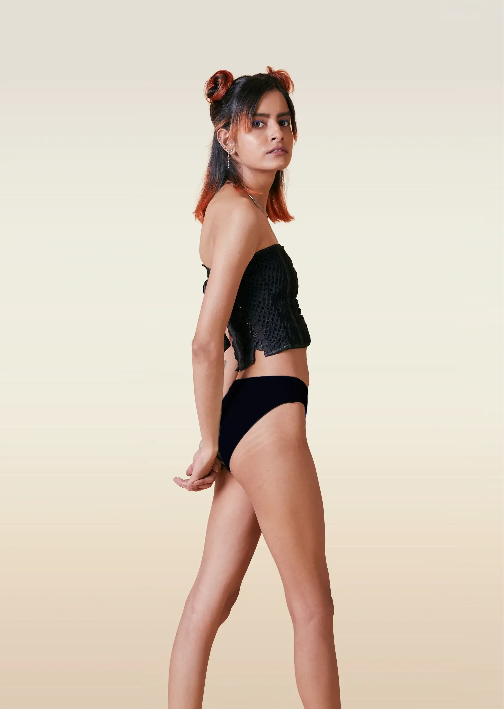 Woman wearing a black top and underwear on a beige background
