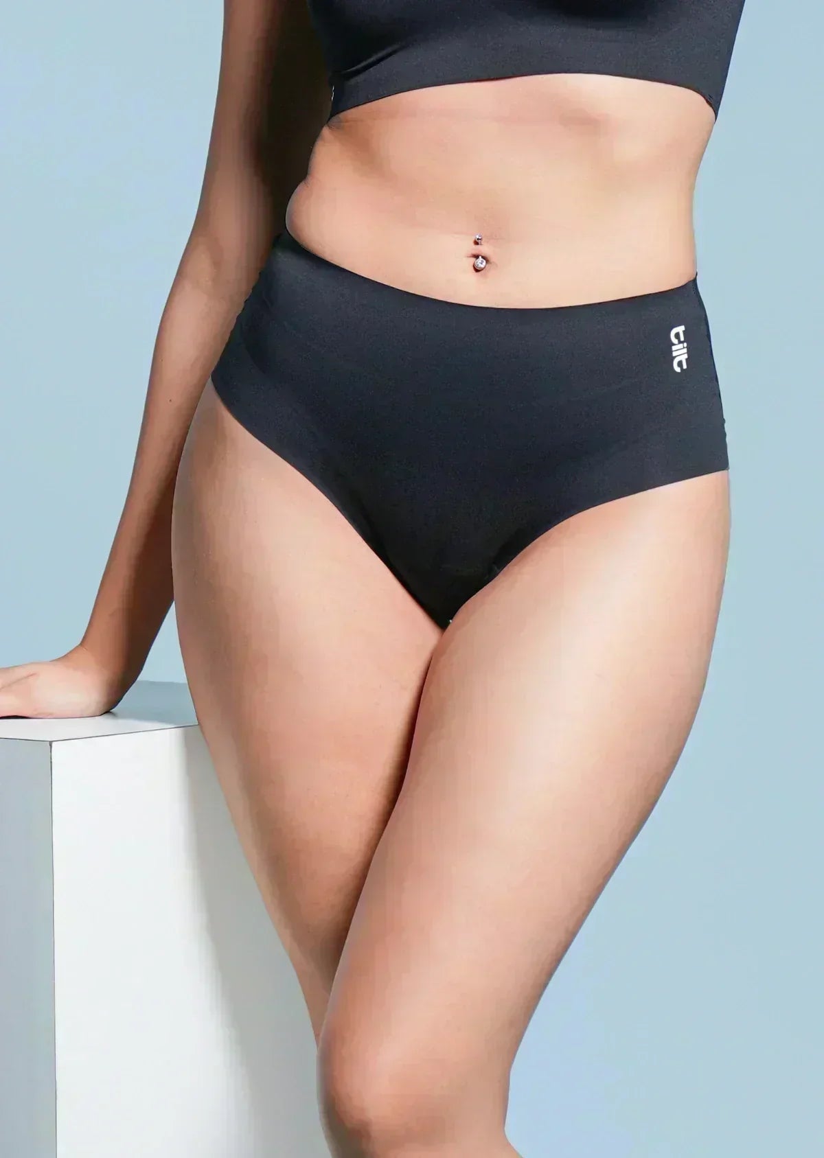 Person wearing black mid-waist underwear on a light blue background