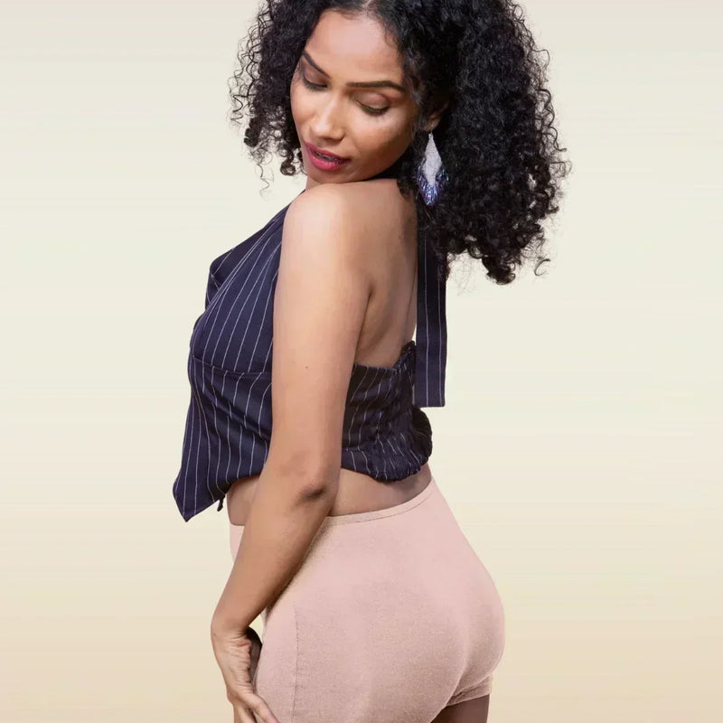 Woman wearing a striped top and beige  boyshorts against a beige background