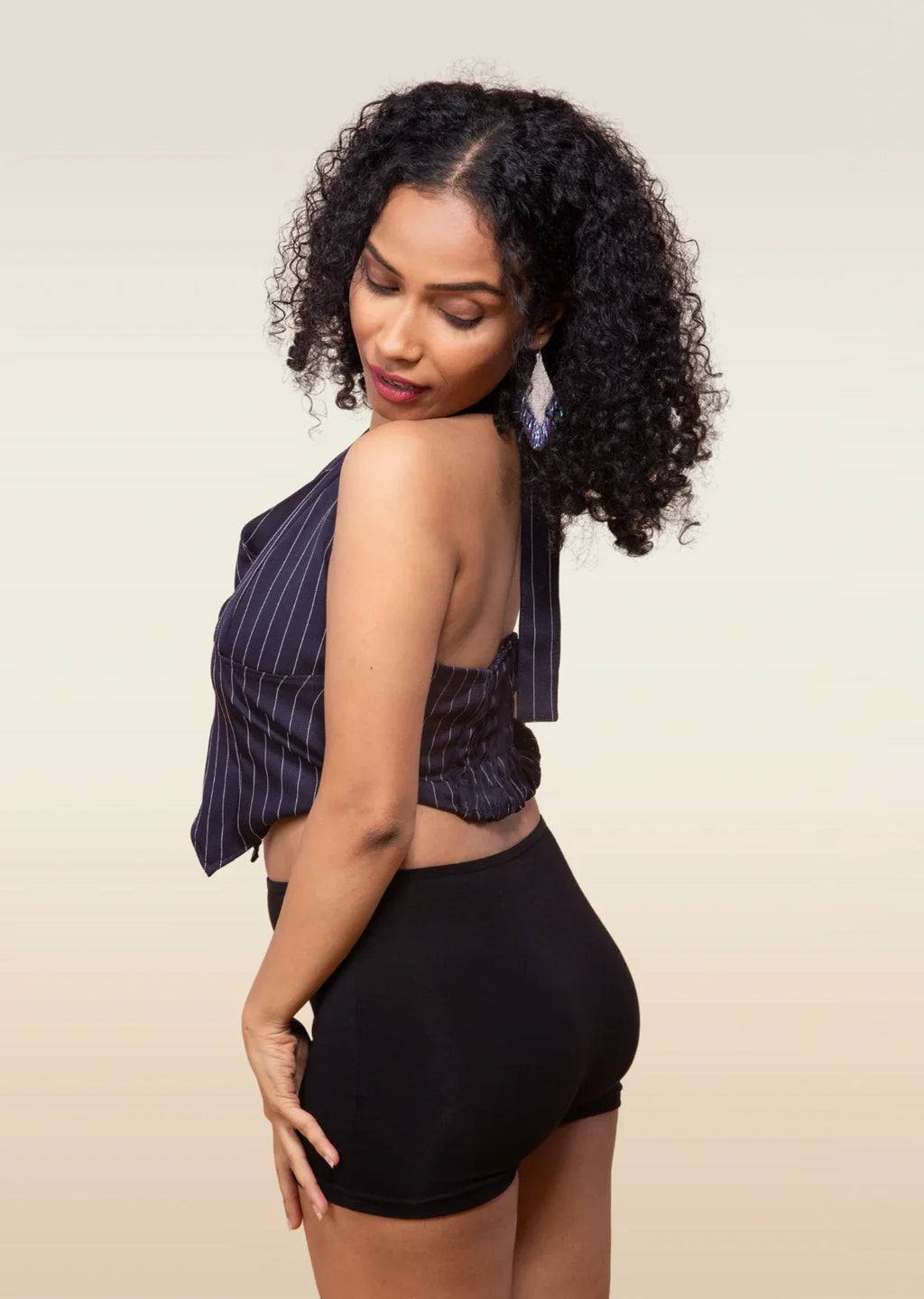 Woman wearing a striped top and black boyshorts against a beige background