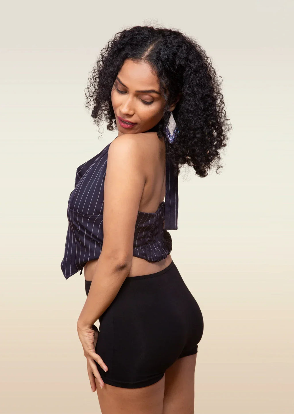 Woman wearing a striped top and black boyshorts against a beige background