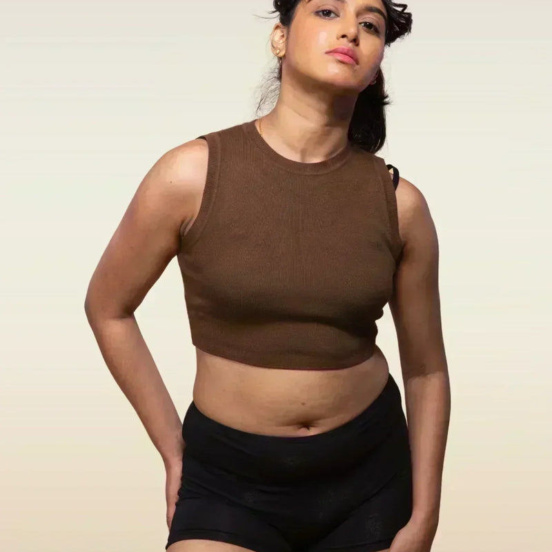 Woman wearing a brown sleeveless top and black boyshorts against a beige background