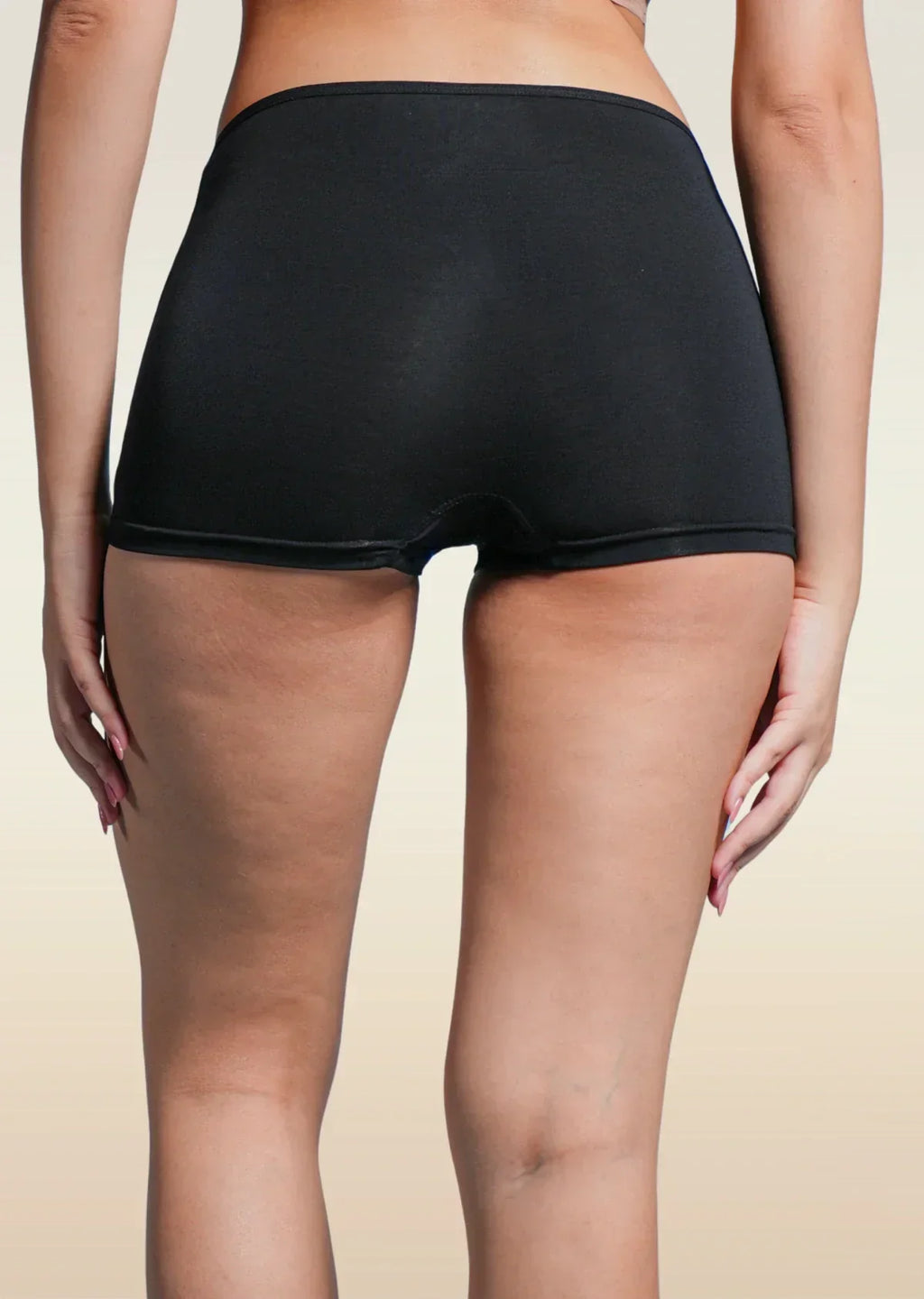 Person wearing black boyshorts  on a beige background