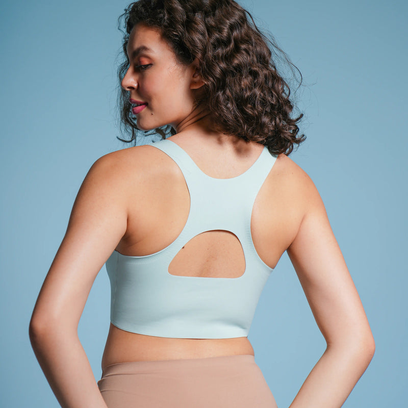 Woman wearing a light blue bra and beige underwear against a blue background