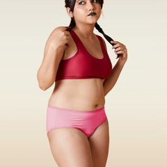 Woman wearing a red sports bra and pink underwear on a beige background