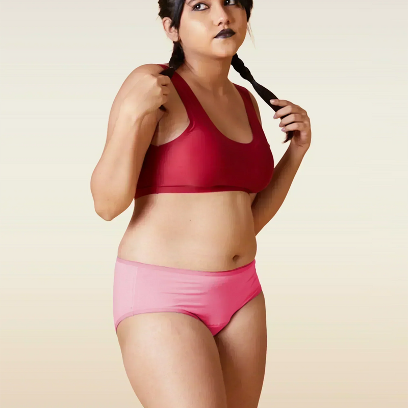 Woman wearing a red sports bra and pink underwear on a beige background