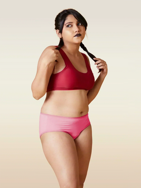 Woman wearing a red sports bra and pink underwear on a beige background
