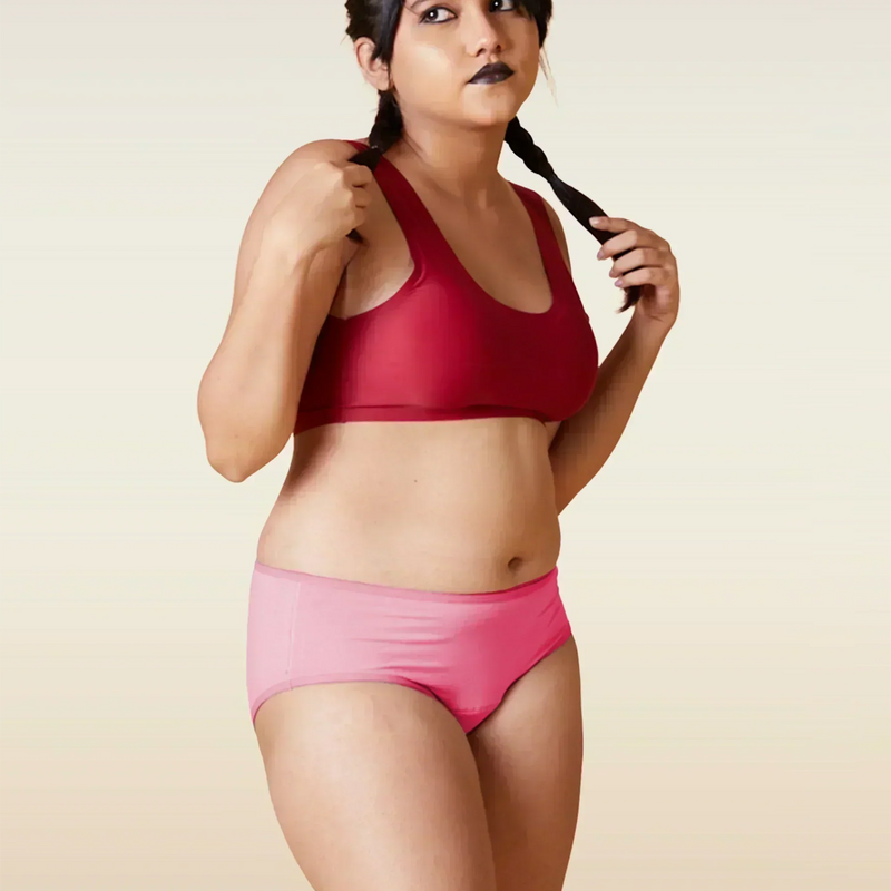 Woman wearing a red sports bra and pink underwear on a beige background