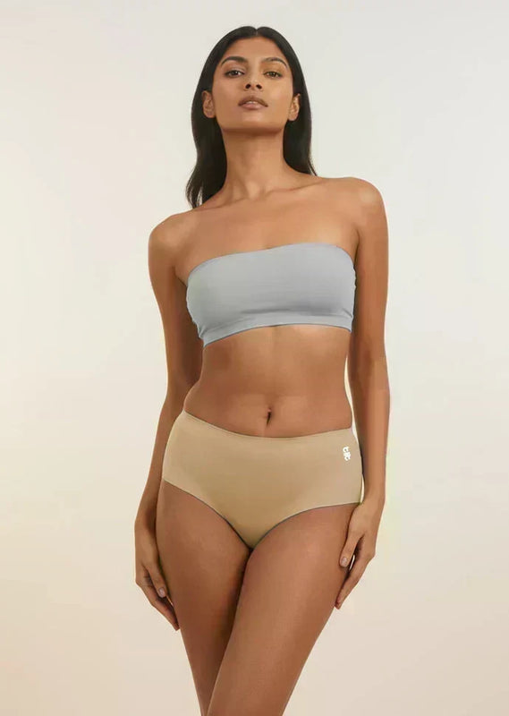 Woman wearing a light blue strapless top and beige mid-waist underwear on a plain background