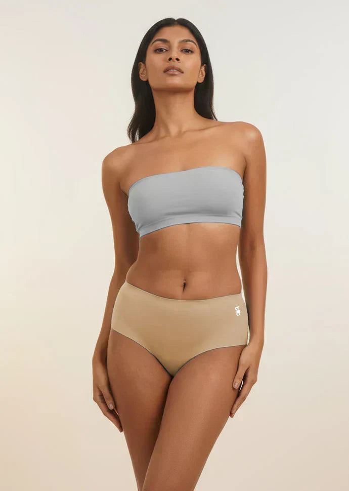 Woman wearing a light blue strapless top and beige mid-waist underwear on a plain background