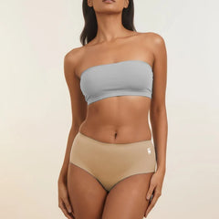 Woman wearing a light blue strapless top and beige mid-waist underwear on a plain background
