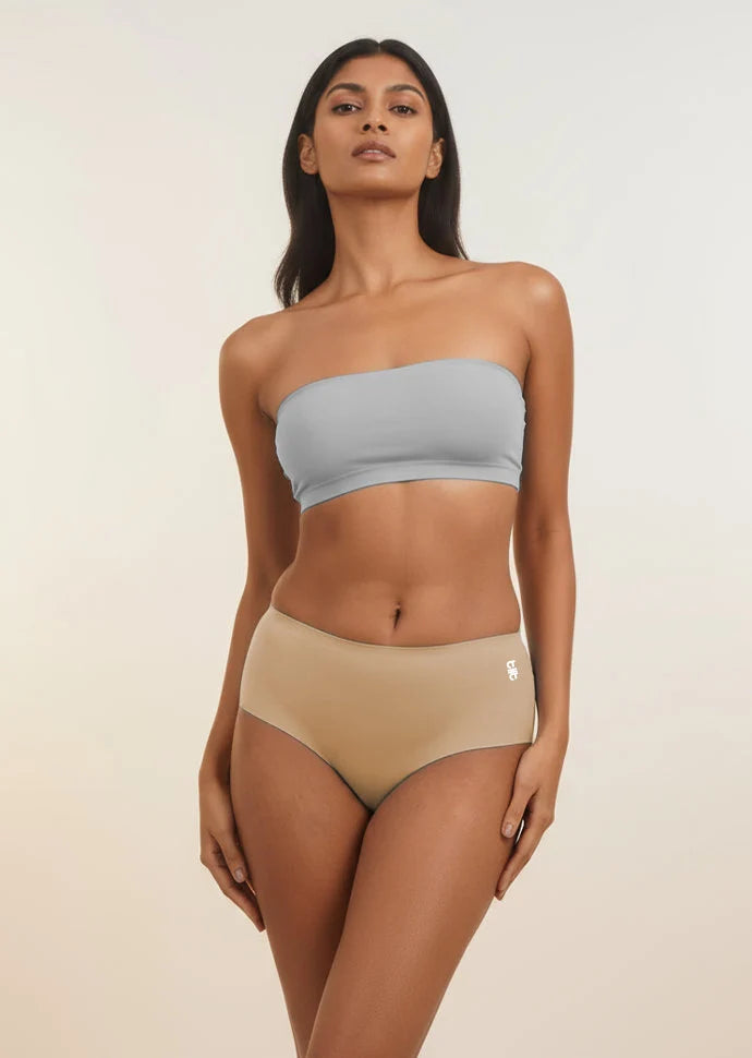 Woman wearing a light blue strapless top and beige mid-waist underwear on a plain background