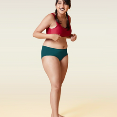 Woman wearing a red sports bra and teal underwear on a beige background 
