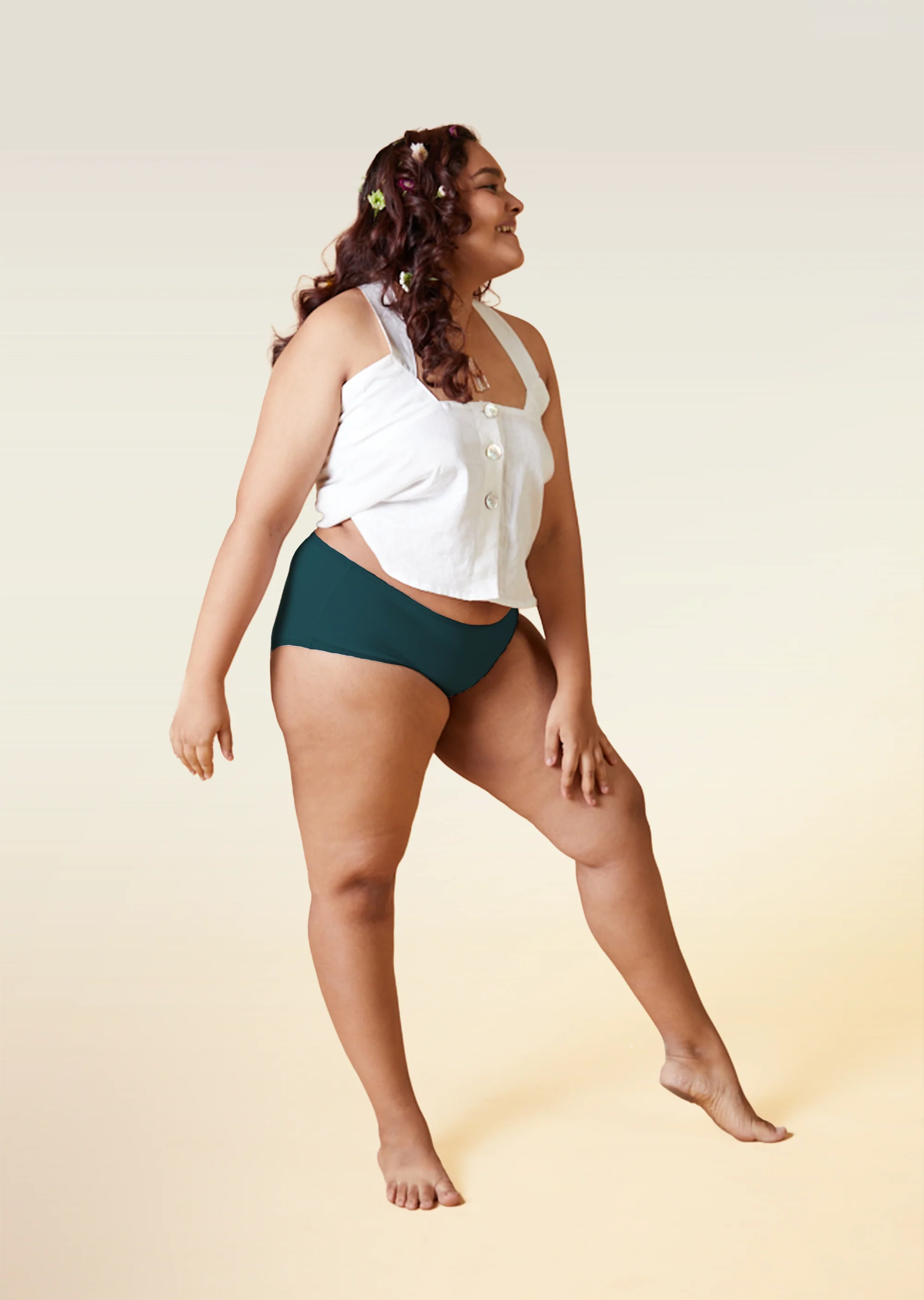 Woman wearing a white top and teal underwear on a beige background