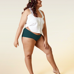 Woman wearing a white top and teal underwear on a beige background