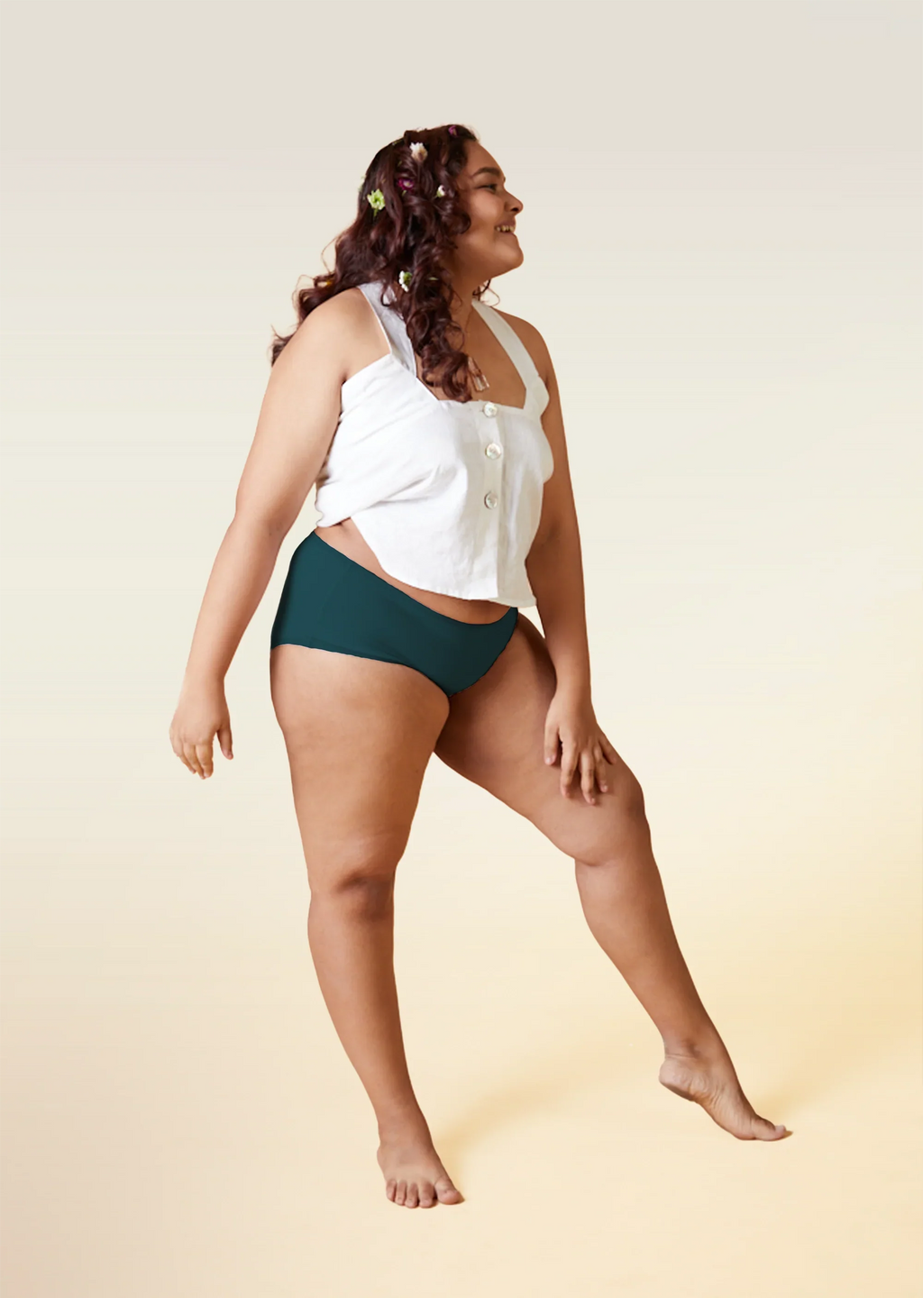 Woman wearing a white top and teal underwear on a beige background