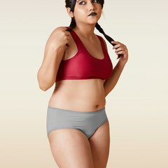 Woman wearing a red sports bra and gray underwear on a beige background