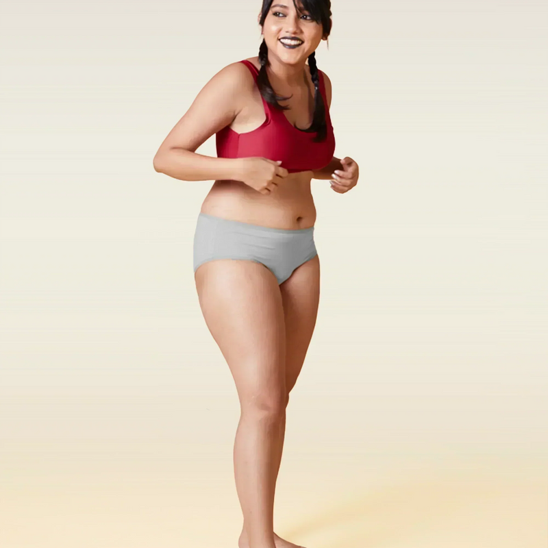Woman wearing a red sports bra and gray underwear on a gradient background
