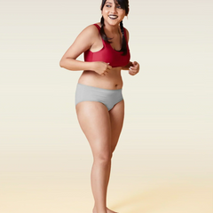Woman wearing a red sports bra and gray underwear on a gradient background
