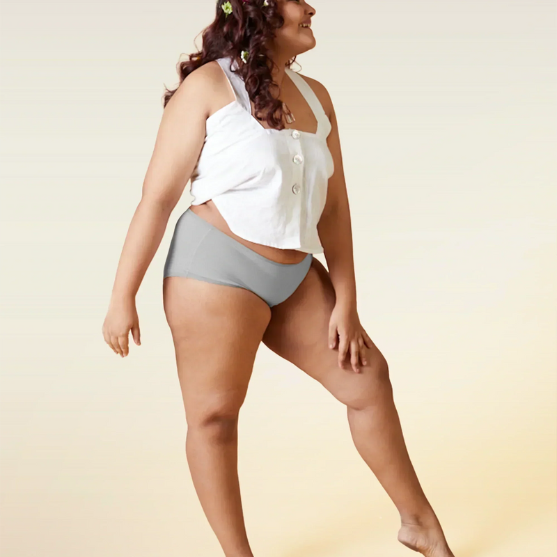 Woman wearing a white top and gray underwear on a beige background