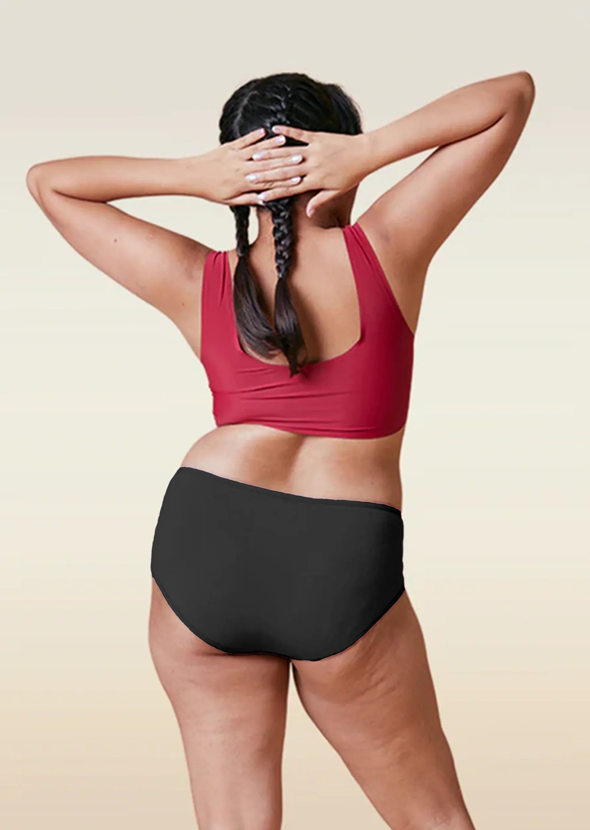Person wearing a red sports bra and black high-waisted underwear on a beige background