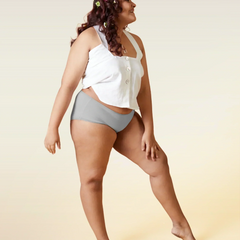 Woman wearing a white top and gray underwear on a beige background