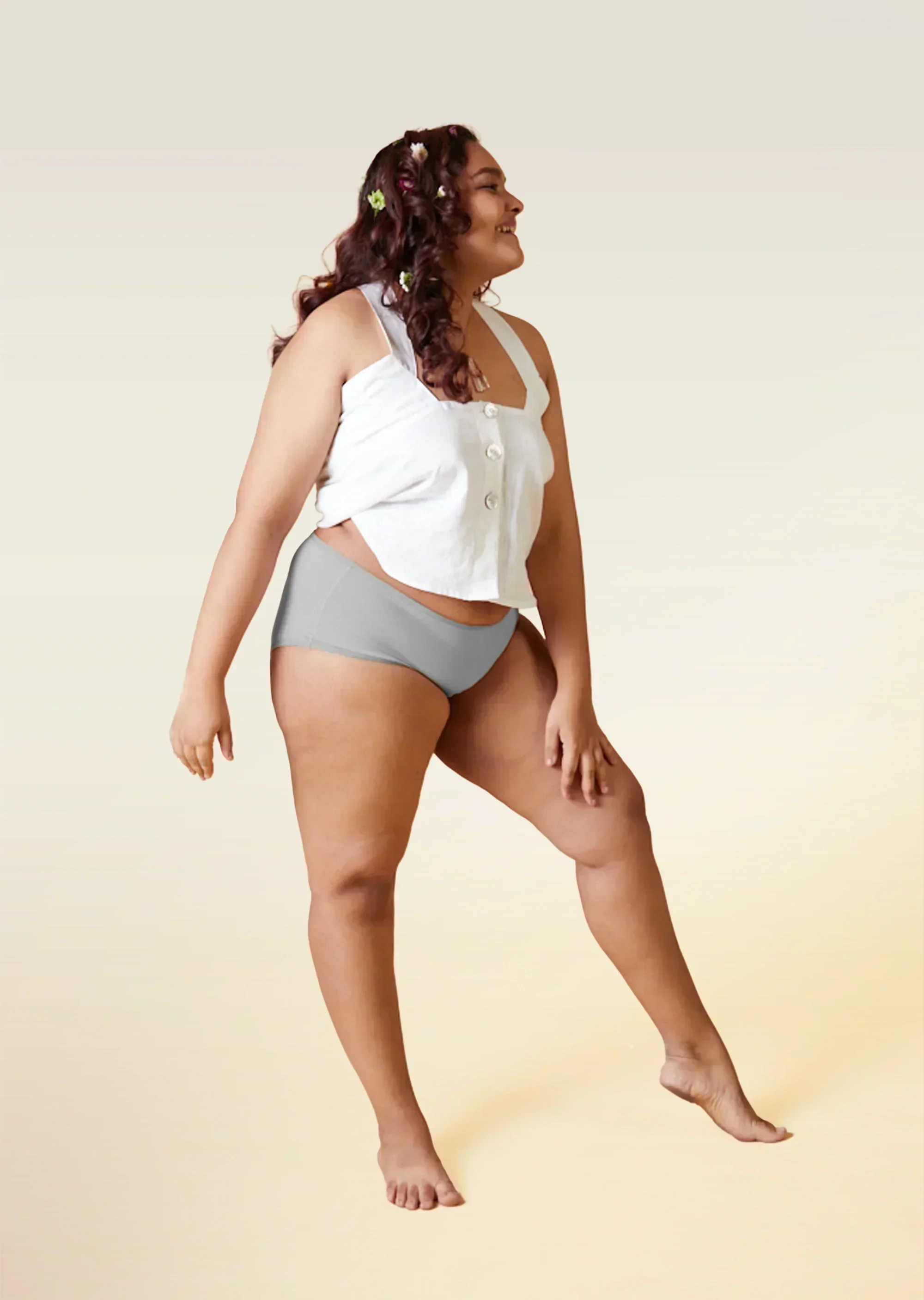 Woman wearing a white top and gray underwear on a beige background