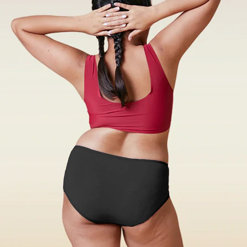 Person wearing a red sports bra and black high-waisted underwear on a beige background