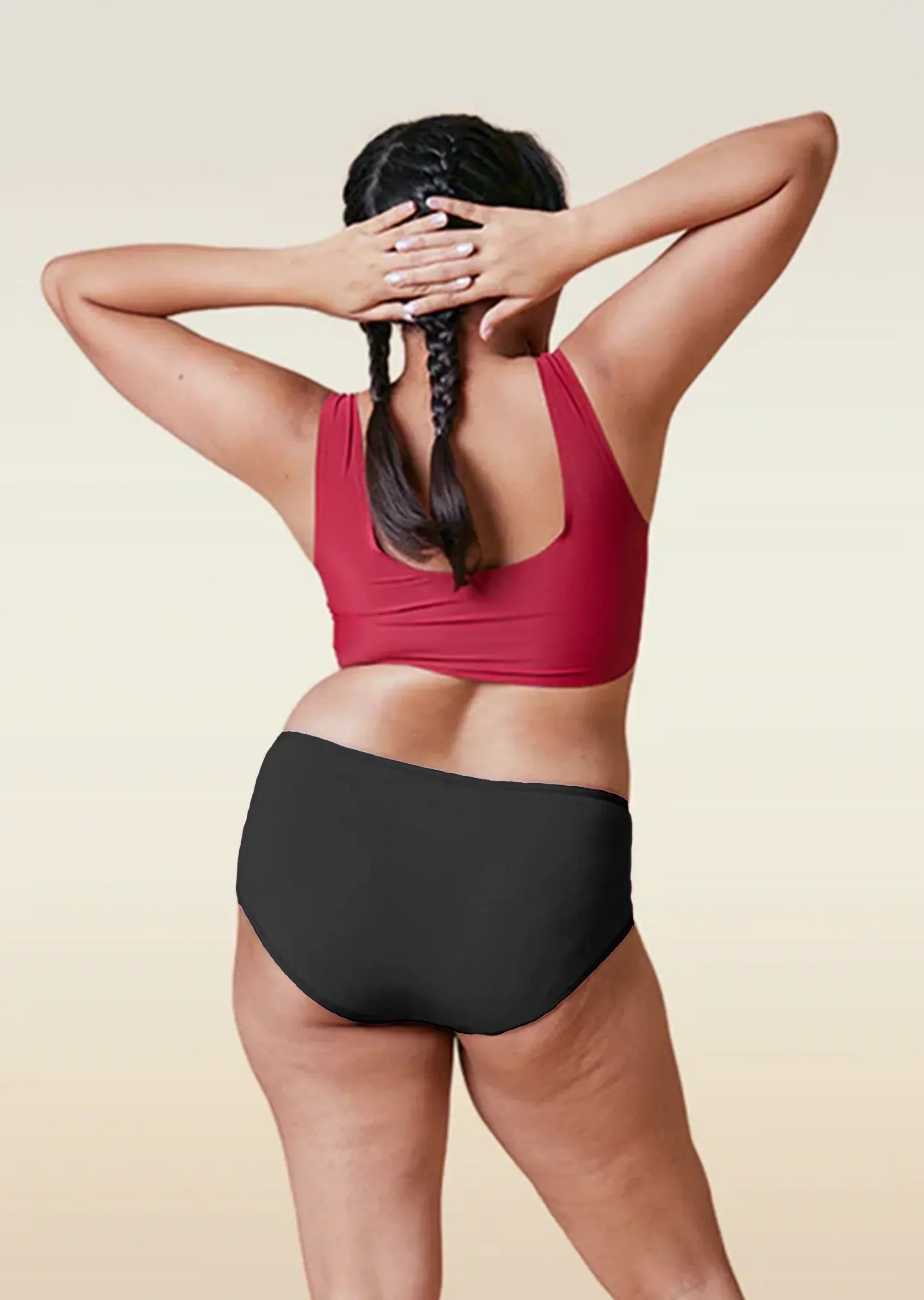 Person wearing a red sports bra and black high-waisted underwear on a beige background