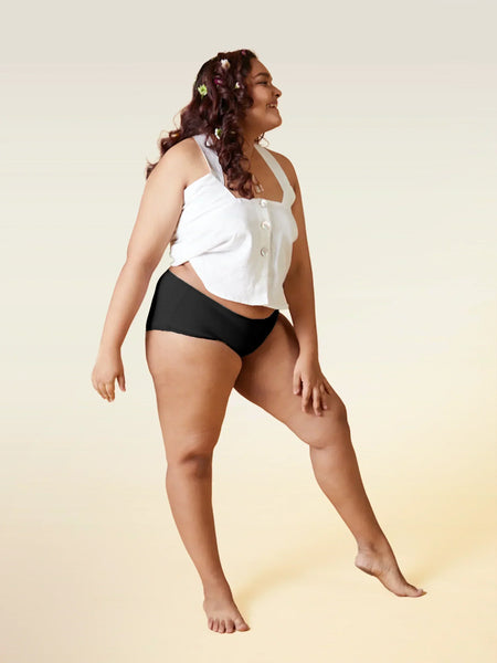 Woman wearing a white top and black underwear on a beige background