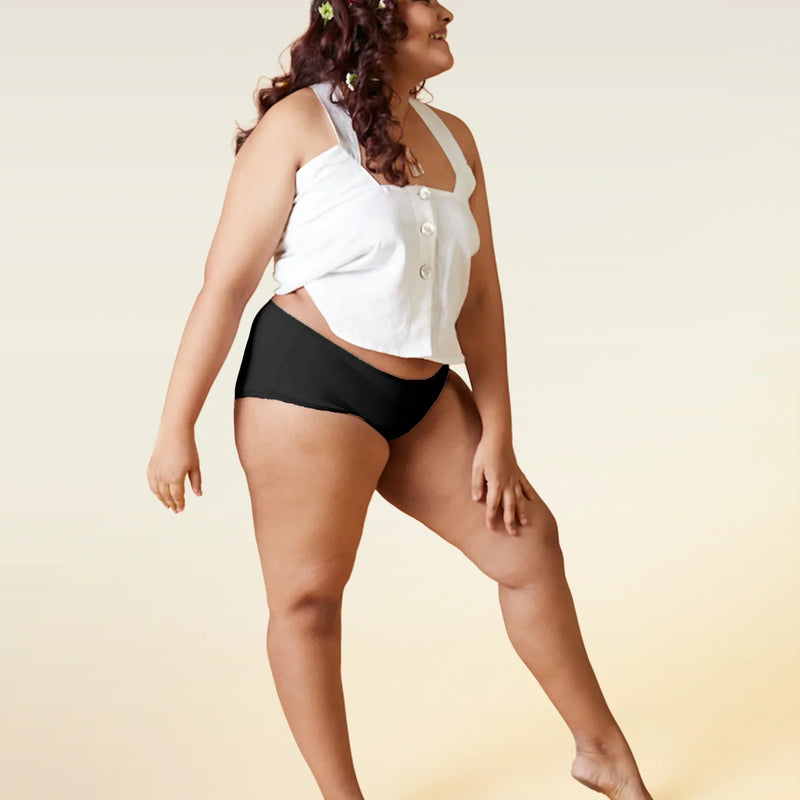 Woman wearing a white top and black underwear on a beige background