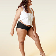 Woman wearing a white top and black underwear on a beige background