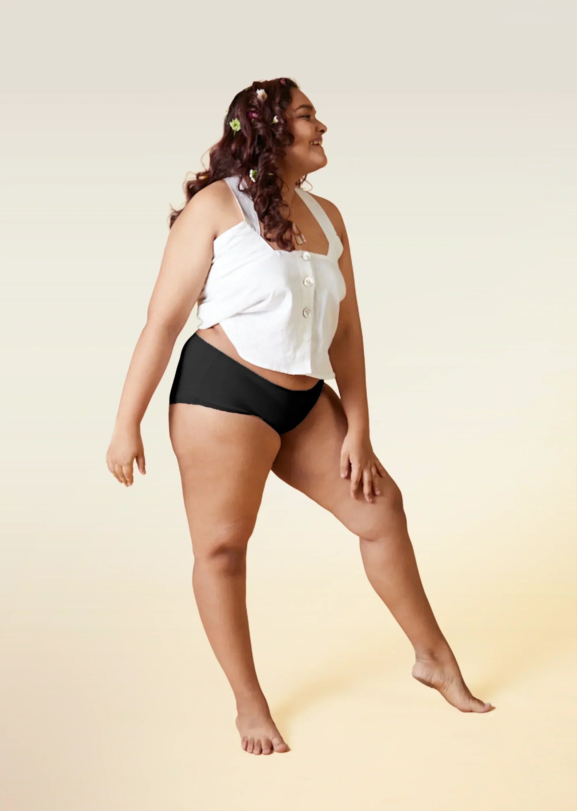 Woman wearing a white top and black underwear on a beige background