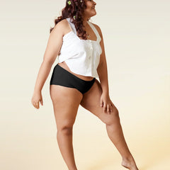 Woman wearing a white top and black underwear on a beige background