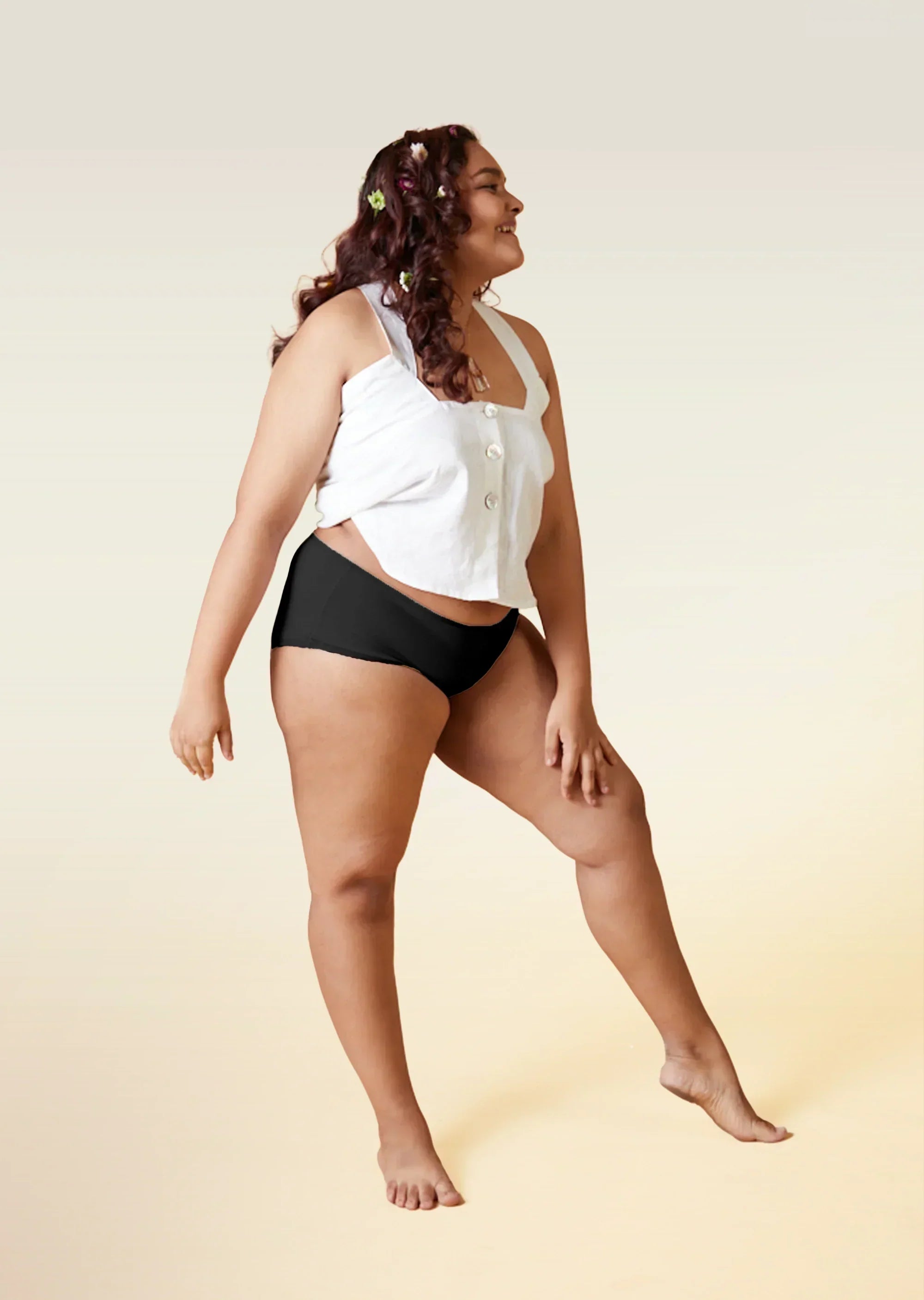 Woman wearing a white top and black underwear on a beige background