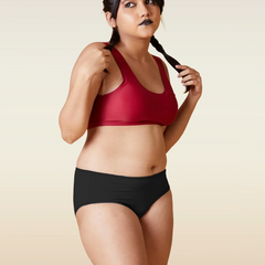 Woman wearing a red sports bra and black underwear on a beige background