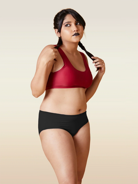 Woman wearing a red sports bra and black underwear on a beige background