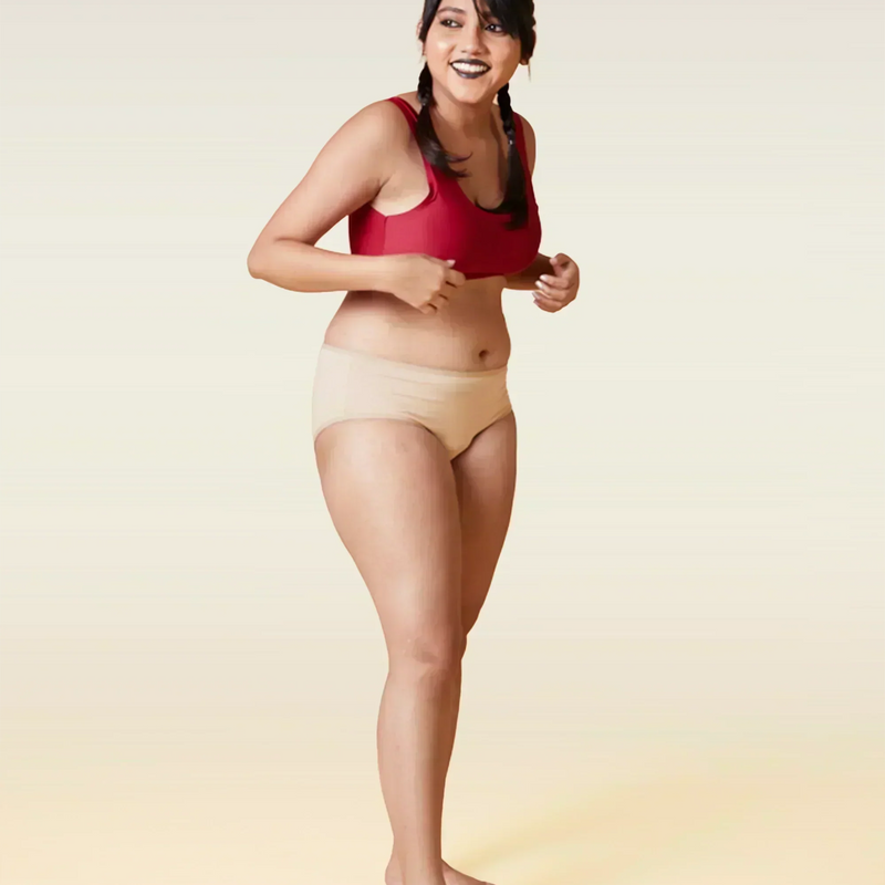 Woman wearing a red sports bra and beige underwear on a beige background