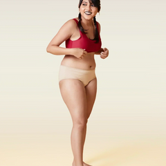 Woman wearing a red sports bra and beige underwear on a beige background