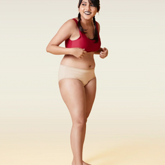 Woman wearing a red sports bra and beige underwear on a beige background