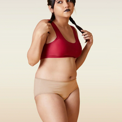 Woman wearing a red sports bra and beige underwear on a beige background