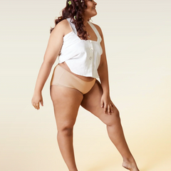 Woman wearing a white top and beige underwear on a beige background