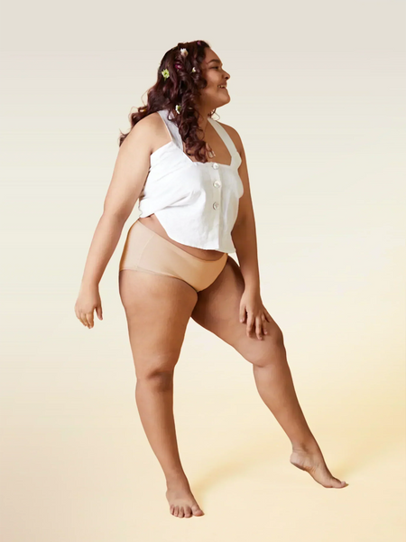 Woman wearing a white top and beige underwear on a beige background