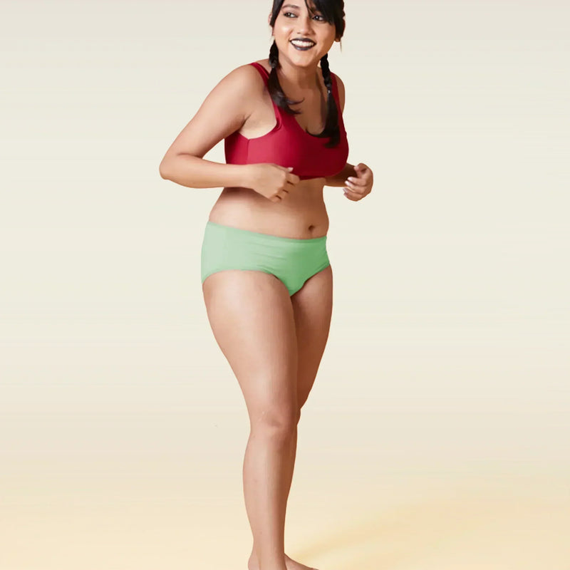 Woman wearing a red sports bra and green underwear on a gradient background