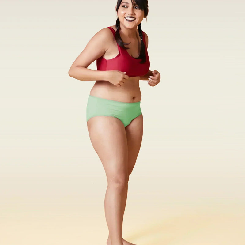 Woman wearing a red sports bra and green underwear on a gradient background