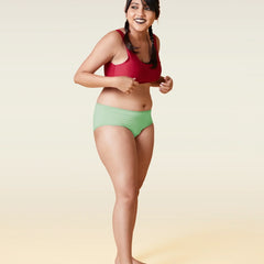 Woman wearing a red sports bra and green underwear on a gradient background